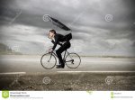 uomo-d-affari-che-guida-una-bici-con-un-ombrello-38123644[1].jpg